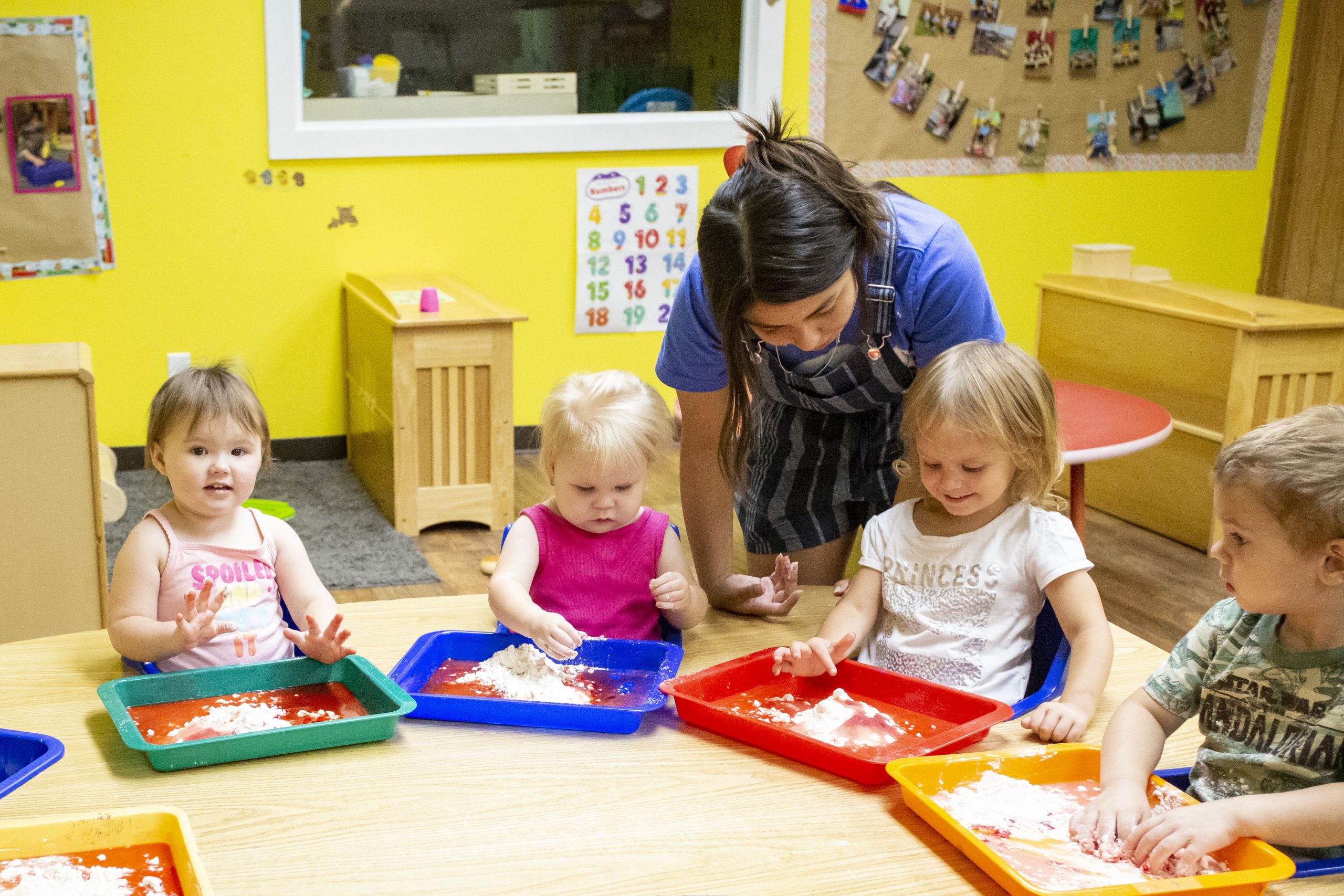 2022 SS_kids_006A0106 Stepping Stones Child care playdough making and teach helping, yellow walls, bright primary colors
